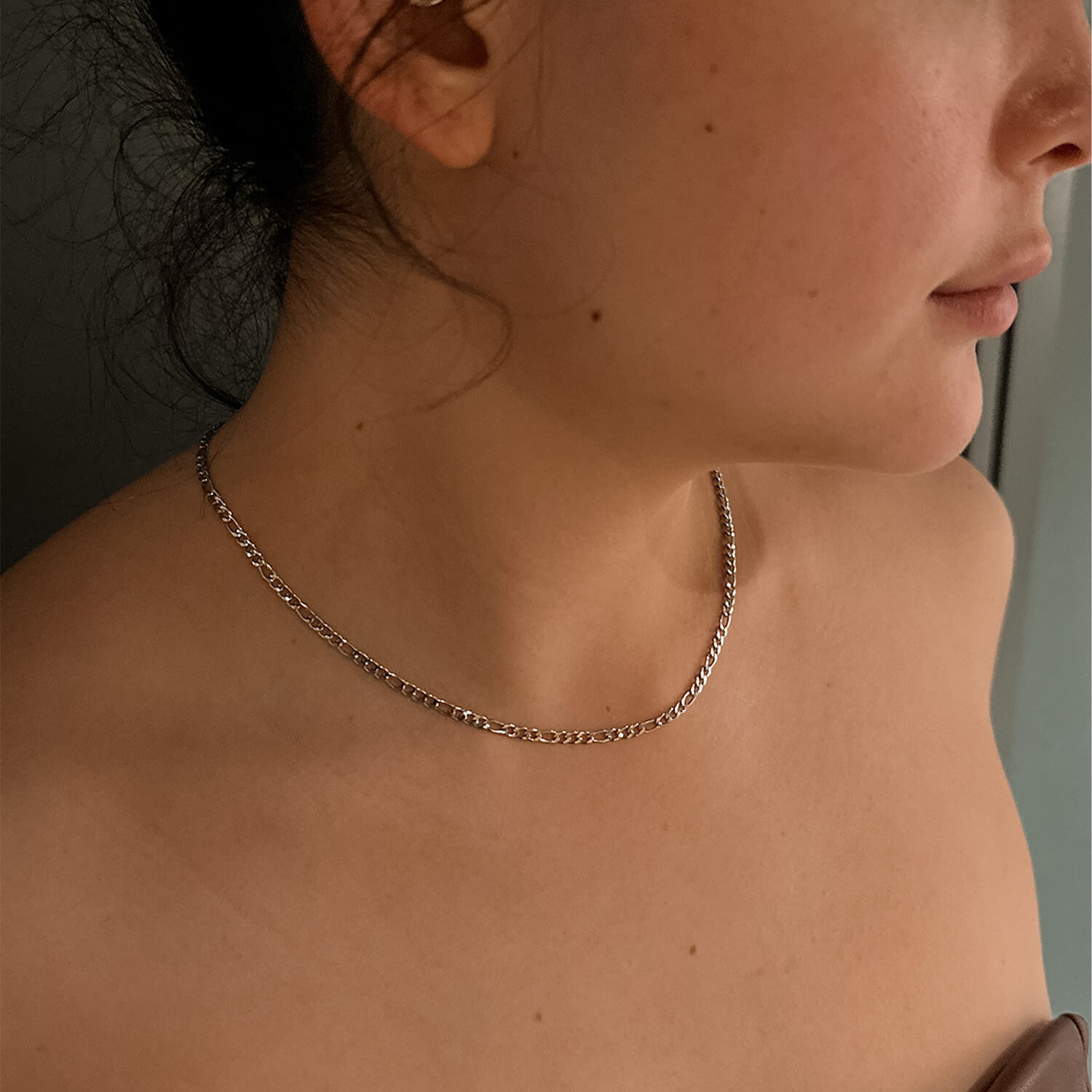 female wearing 3mm silver figaro chain on neck