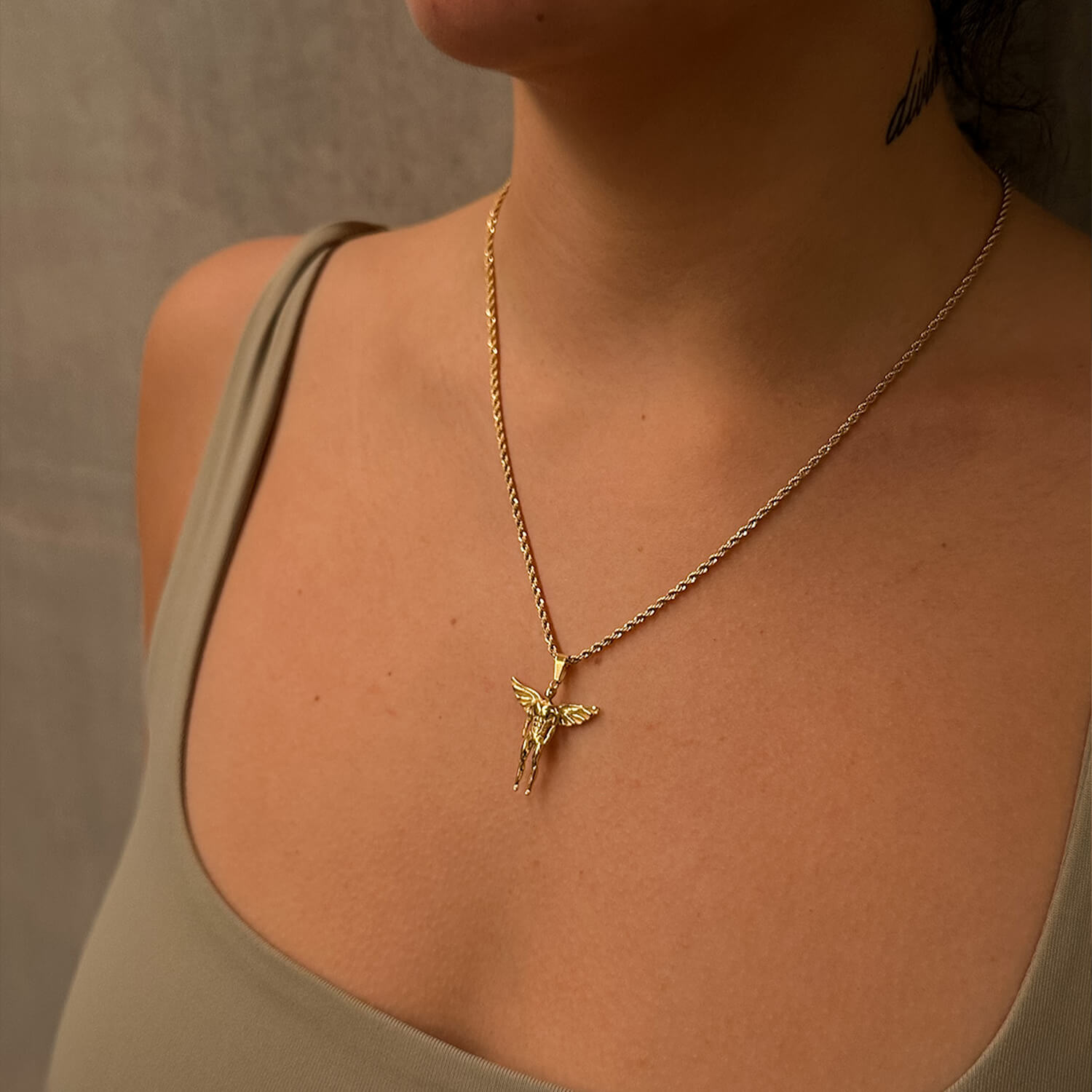 female wearing gold icarus pendant on neck