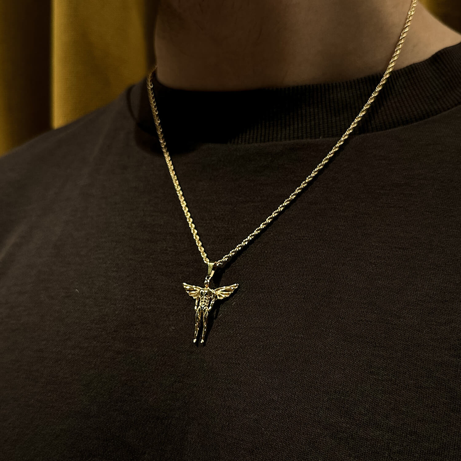 male wearing gold icarus pendant on neck