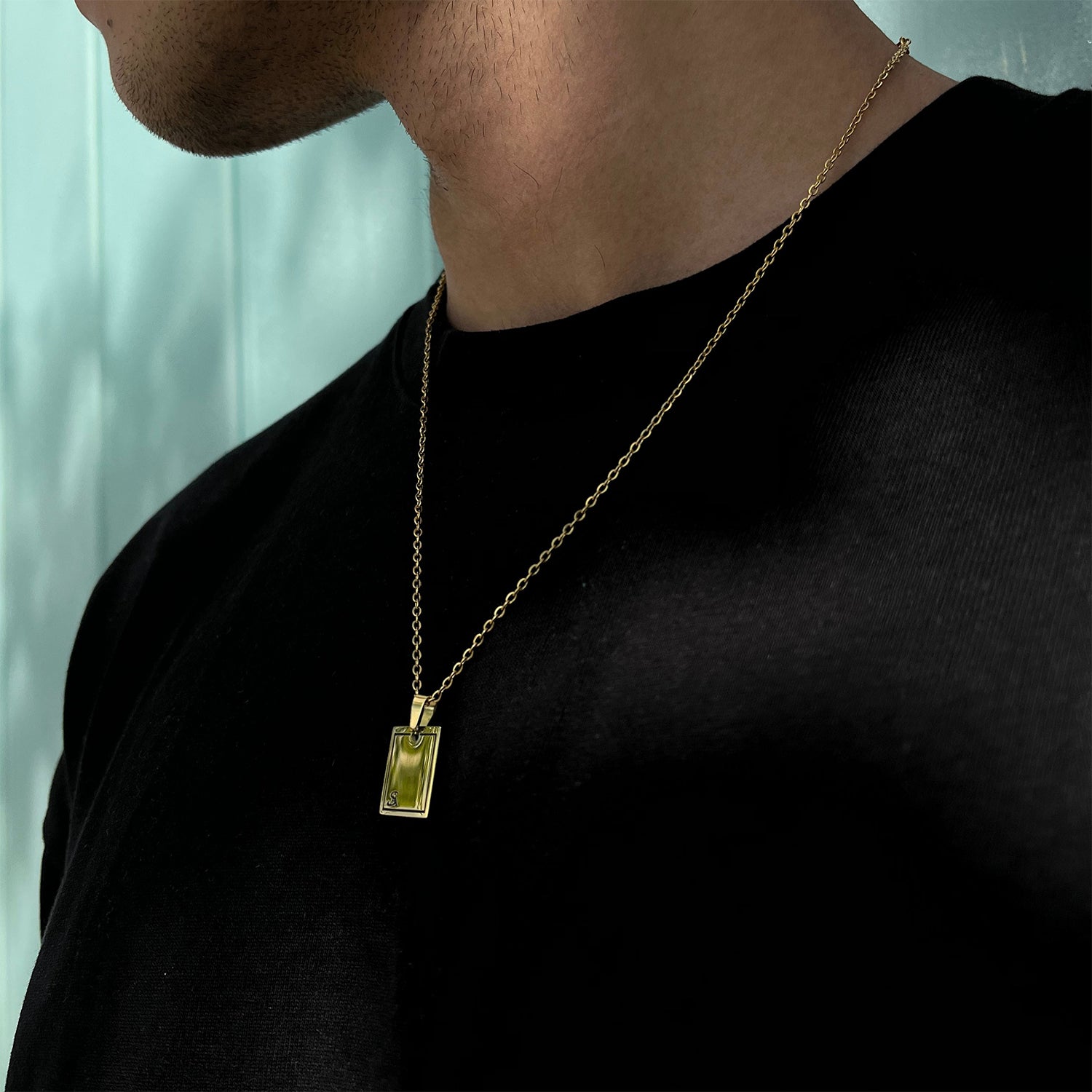 male wearing gold rectangle pendant on neck